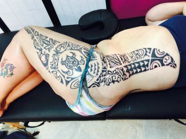 Person showing large tribal tattoo on abdomen and legs.