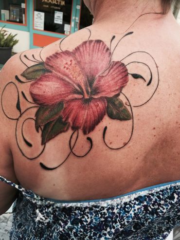 Colorful hibiscus flower tattoo on a shoulder.