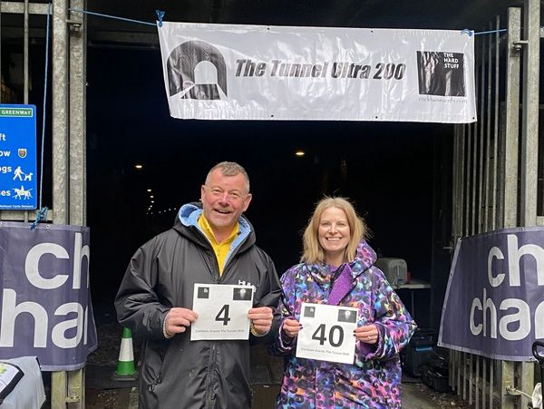 Two people holding race bibs smiling at the finish line.
