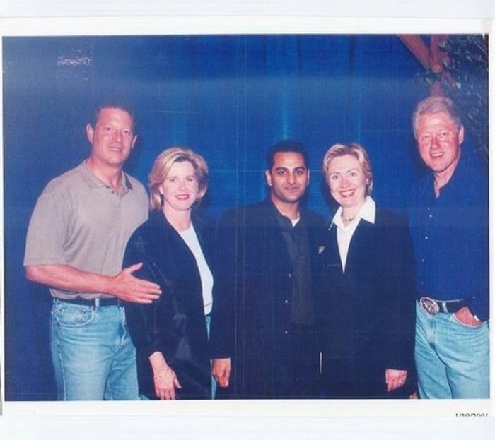 Five people posing together for a photo in formal and casual attire.
