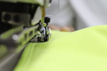 Close-up of a sewing machine stitching neon green fabric.