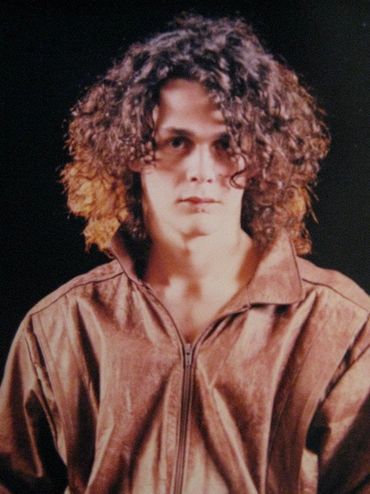 Mito Mora con pelo largo y chaqueta de cuero café mirando al frente