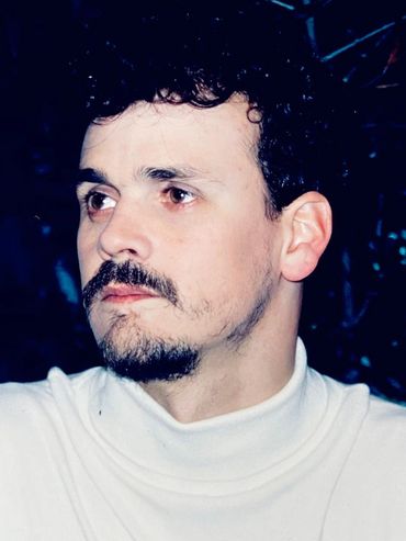 Close up de Mito Mora mirando hacia la izquierda con un beattle blanco