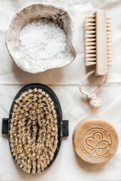 Flat lay of natural bath accessories including brushes, soap, and bath salts.