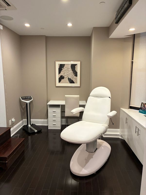 A modern medical or spa room with a white reclining chair and desk.
