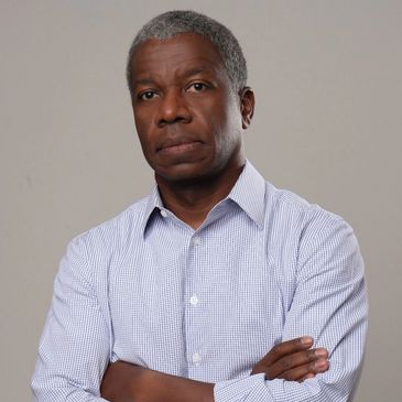 Serious man with arms crossed wearing a checkered shirt.
