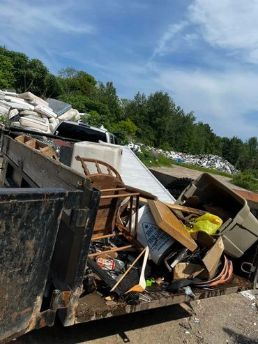 Variety of furniture and household junk in dump trailer.