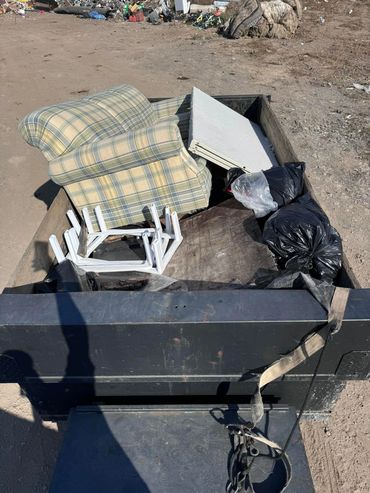Various household items, mostly furniture in a dump trailer