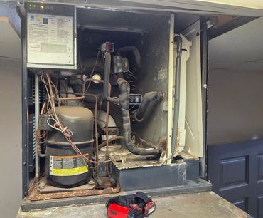Interior view of an old, rusty refrigeration or HVAC unit with exposed components.