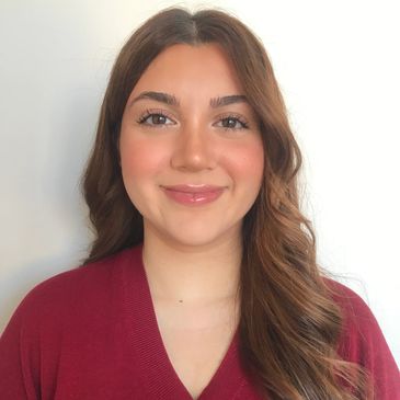 Smiling woman with long wavy hair wearing a red sweater.