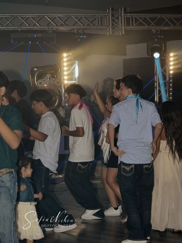 Group of young people dancing at a party with colorful lights and balloons.