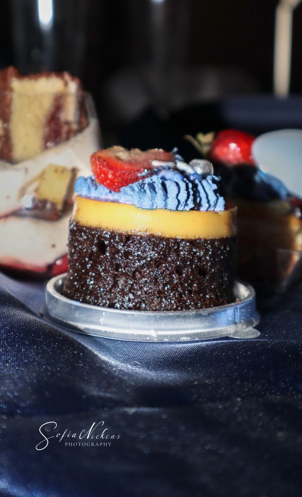 Chocolate cake with yellow frosting and blue cream topped with a strawberry.