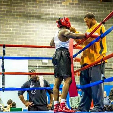 A coach explaining to a man in a boxing ring