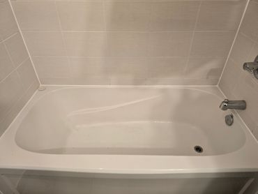 Bathtub with freshly applied white caulking along tub edge