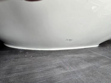White bathtub base sealed with caulking where it meets tiled floor