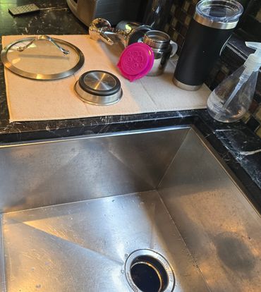 Caulking along a kitchen countertop edge near a stainless steel sink and backsplash.