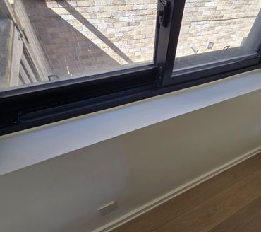 Interior window sill with fresh caulking along frame and wall edges