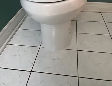 Toilet base sealed with caulking on tiled bathroom floor