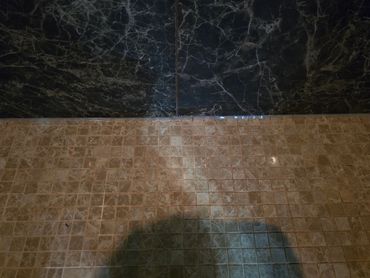 Shower floor tile meeting wall tile with sealed caulking joint