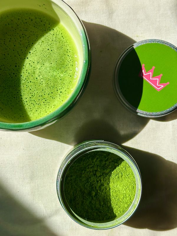 Green matcha tea with powder and a container lid.