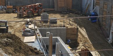 Construction site with concrete foundation work and heavy machinery.