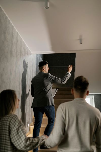 A man in a suit leads a group up stairs, holding a clipboard.