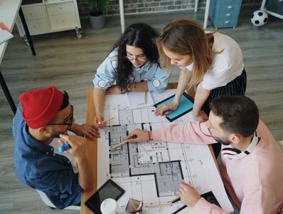 Group of four people discussing architectural plans at a table.