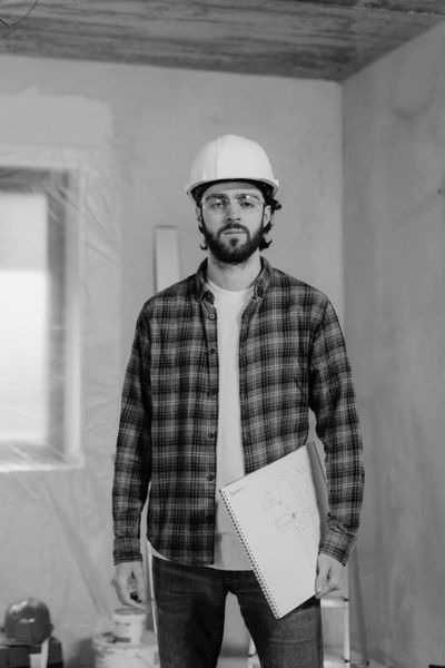 Construction worker in a hard hat holding blueprints on a building site.