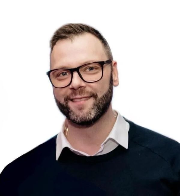 Ein Mann mit Brille und Bart lächelt freundlich.