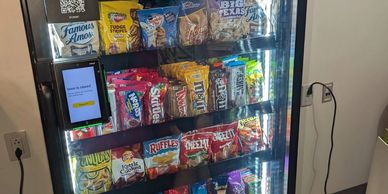 Vending machine stocked with snacks and a touchscreen for checkout.