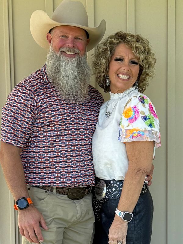 Smiling couple posing together, man in a cowboy hat and woman in colorful blouse.