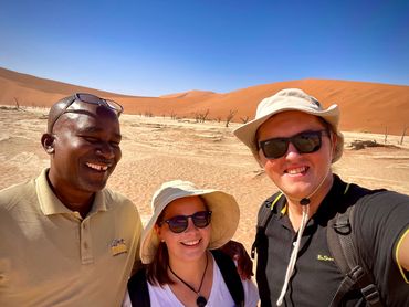 Three people smiling  in Deadvlei, Namib Desert on Namibia private tour