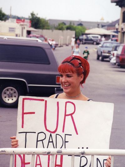 Animal rights protestor holding a sign condemning the wild fur industry and furbearer trapping.