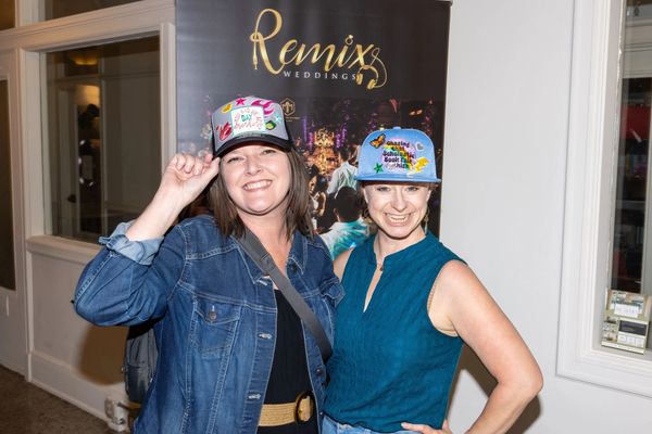 Two women smiling and posing with custom trucker hats