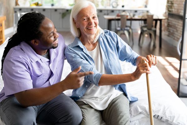 Elderly woman smiling with caregiver at home.
