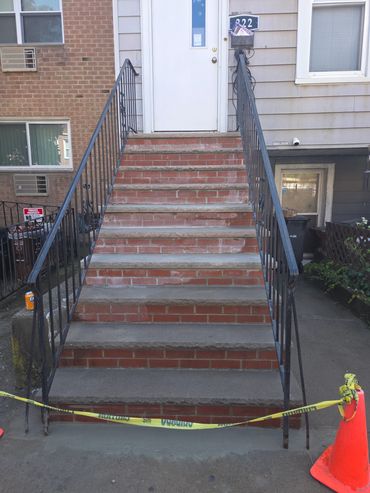 Brick stairs cordoned off with caution tape and an orange cone.