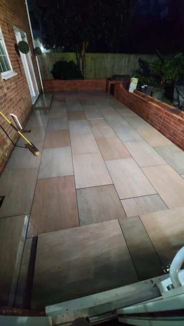 Well-lit backyard patio with tiled floor at night.