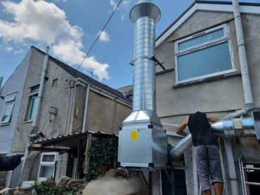 Man working on large ventilation ducts on a residential building.