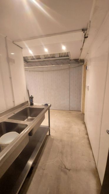 Empty room with large sinks and concrete floor.
