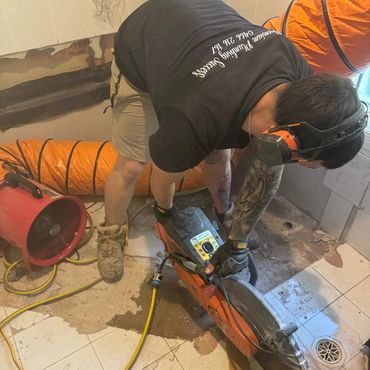 Man cutting tiles with a wet saw in a construction area.