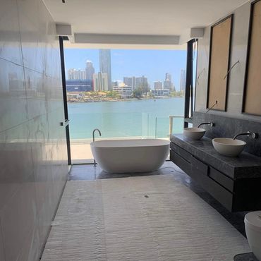Modern bathroom with freestanding tub and city water view.