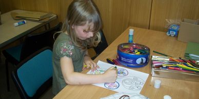 A young lady carefully colouring in her shield artwork.