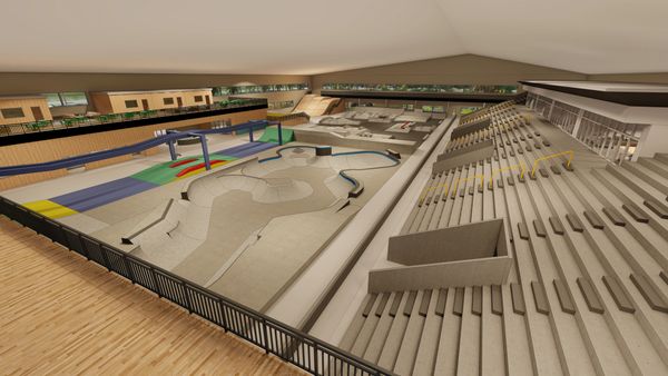 Indoor skatepark with ramps, rails, and seating area.