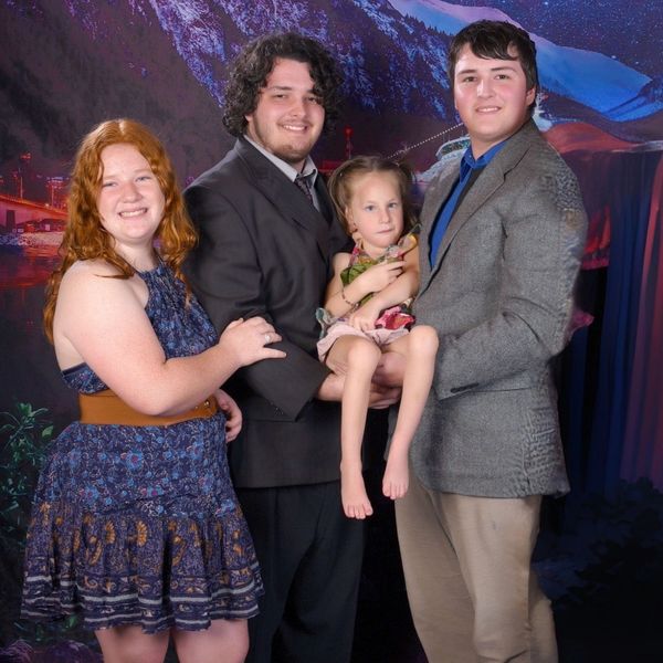 Four people posing together, including a child being held by two adults.