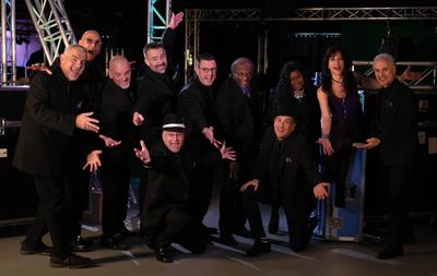 A lively group of performers posing with enthusiasm in black attire.