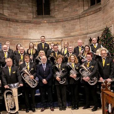 A brass band group posing inside a church with Christmas decorations.