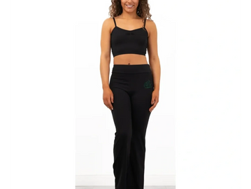 Woman wearing a black crop top and black pants, standing and smiling.