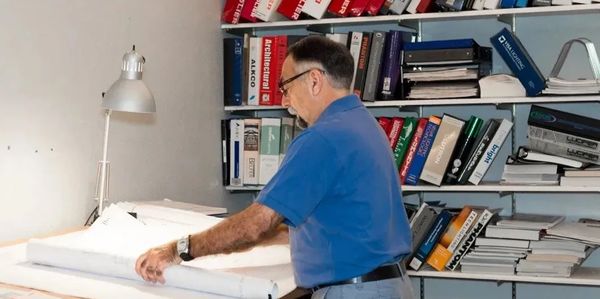 Man reviewing architectural plans in an office.