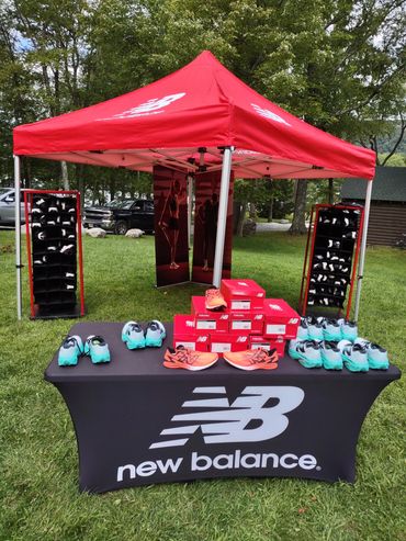 New Balance outdoor display booth with running shoes and branded tent.