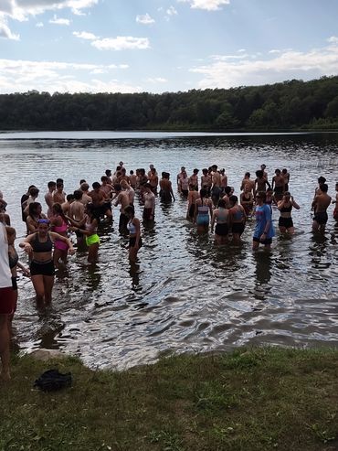 A large group of people wading in a lake on a sunny day.